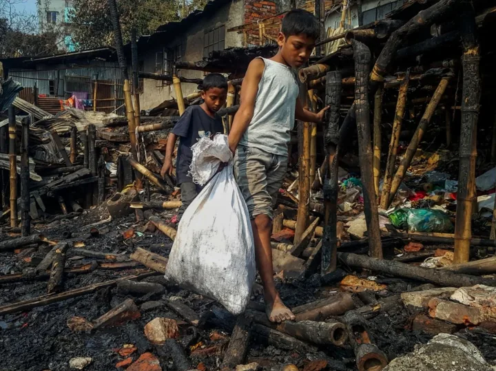 Two boys carry a sack through the remains of burned homes.